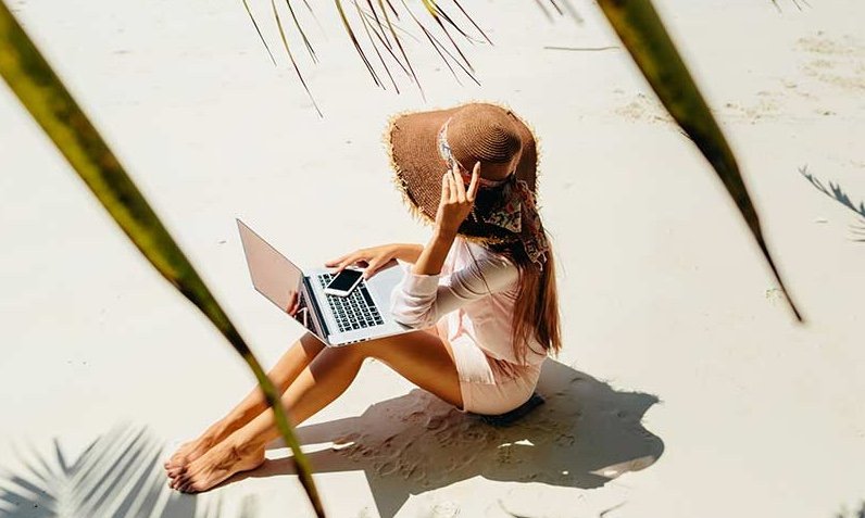 a lady sit on the sand with book in hand